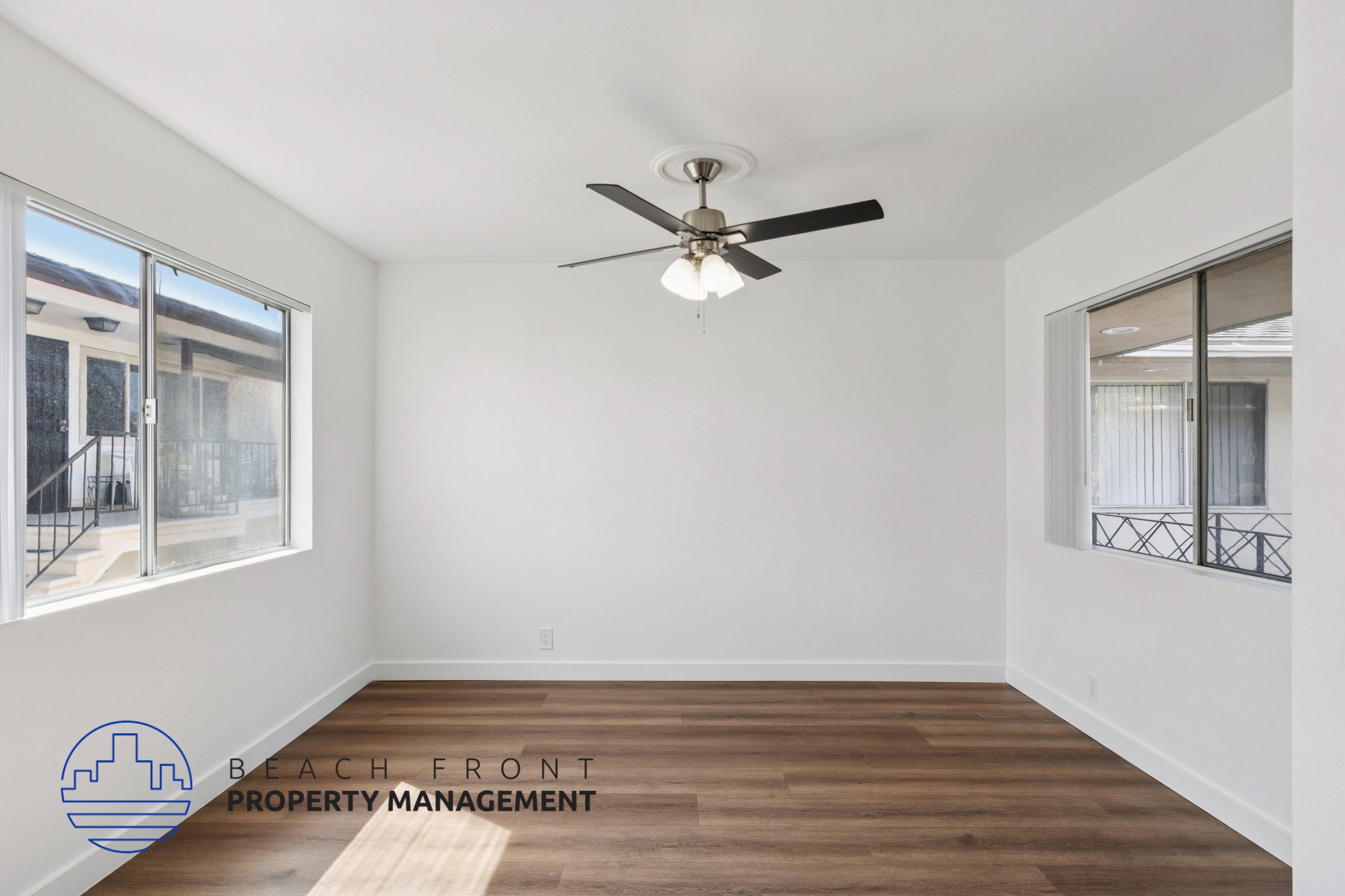 A room with a ceiling fan and wooden flooring.